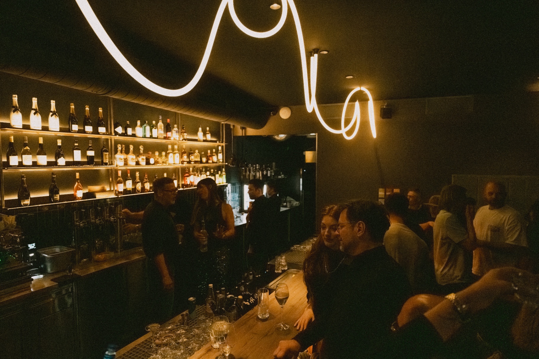 Guests socializing at the bar under the signature light installation