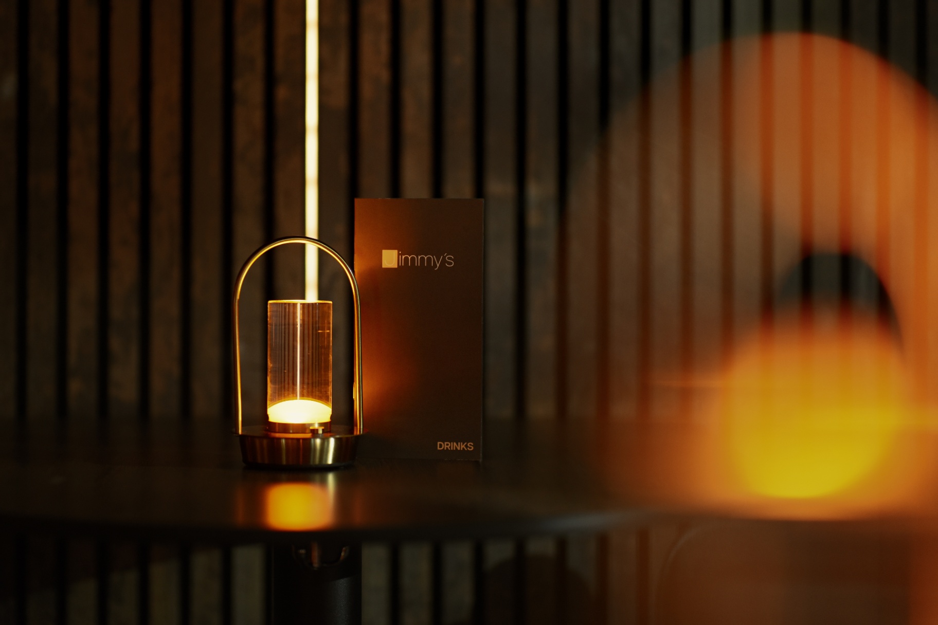 Jimmy's drinks menu beside a warm table lamp